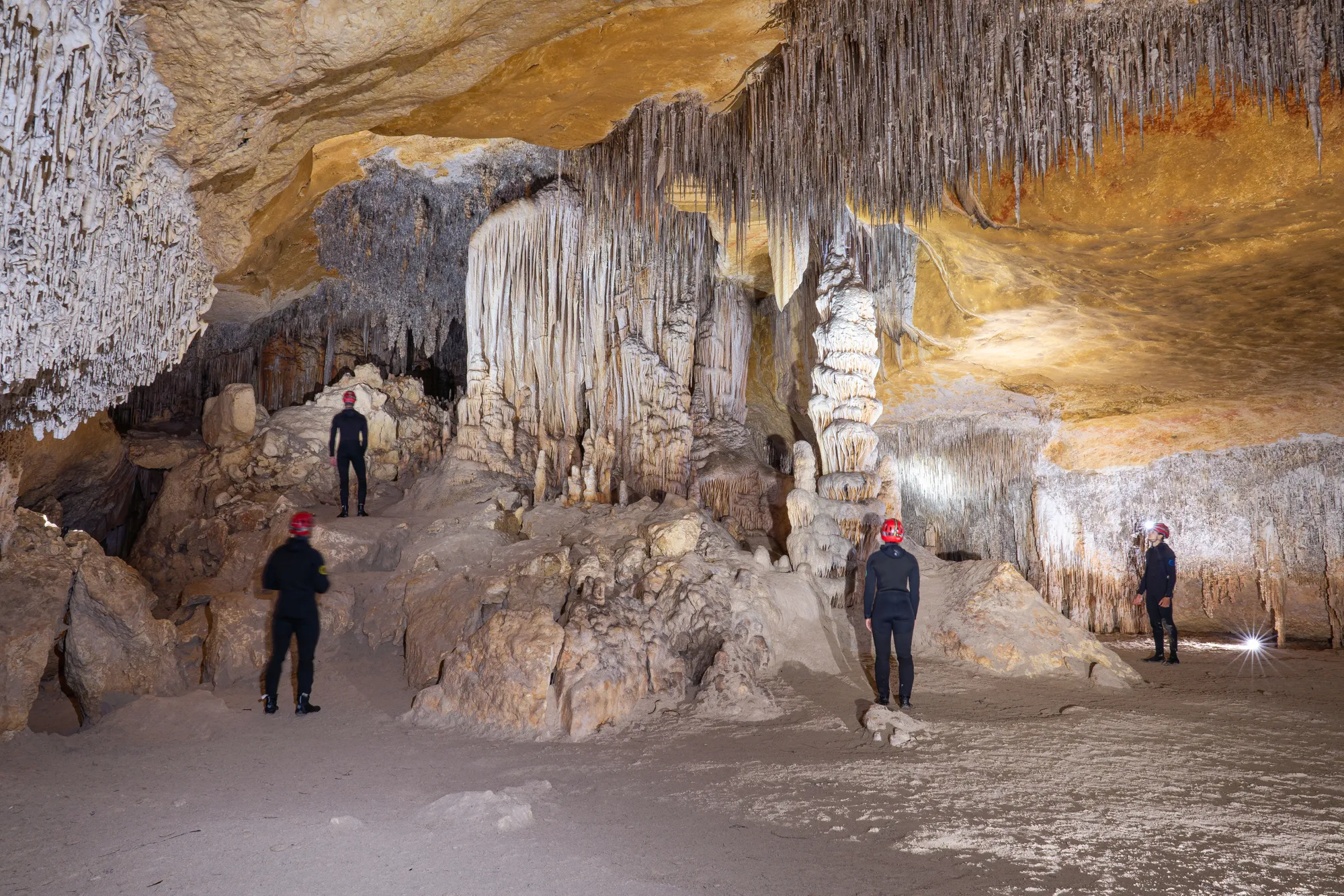 A guide leading a small group through a brightly lit, open sea cave chamber in Mallorca